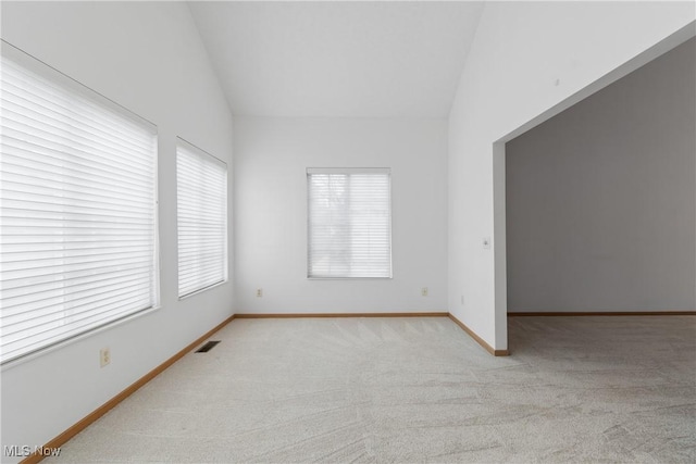 carpeted spare room featuring lofted ceiling