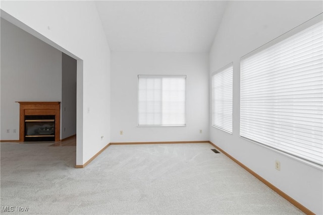 carpeted empty room with vaulted ceiling