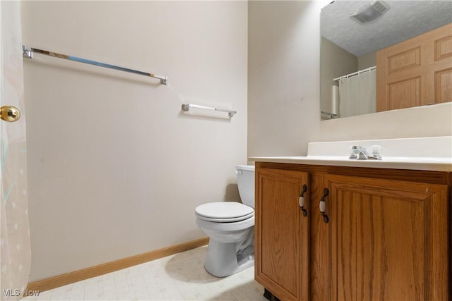 bathroom with vanity, toilet, and a textured ceiling