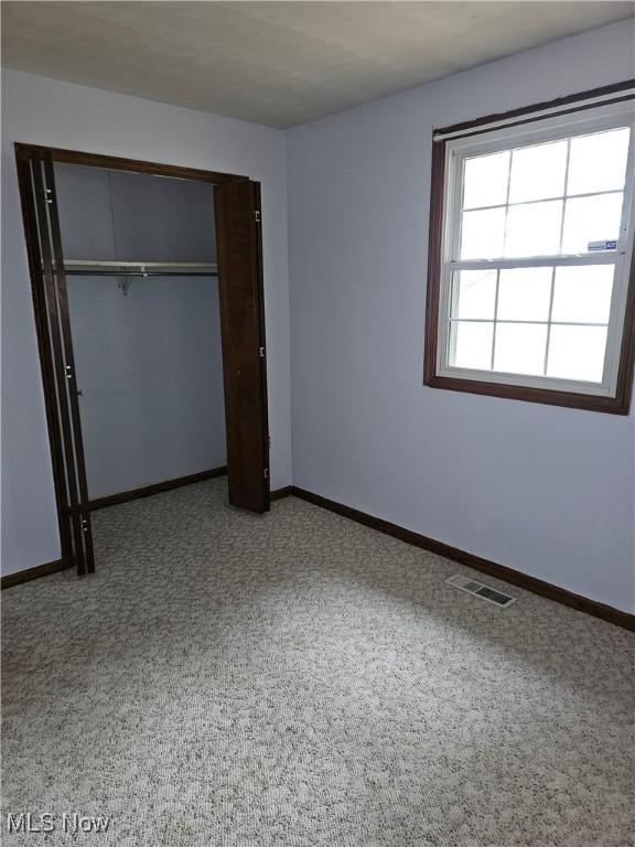 unfurnished bedroom with light colored carpet and a closet