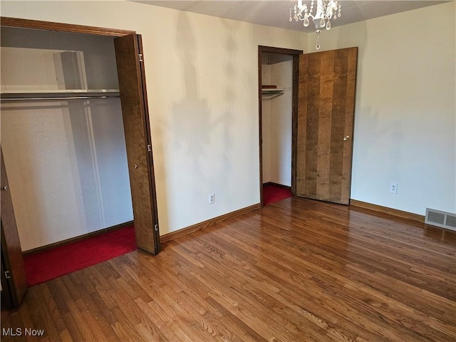 unfurnished bedroom featuring a notable chandelier and hardwood / wood-style flooring