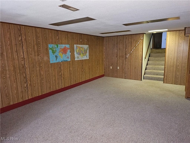 basement with carpet floors, a textured ceiling, and wooden walls