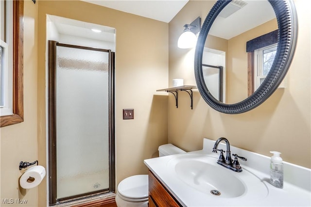 bathroom with a shower with door, vanity, and toilet