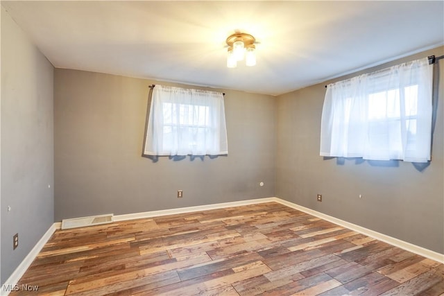 empty room with a wealth of natural light and wood-type flooring