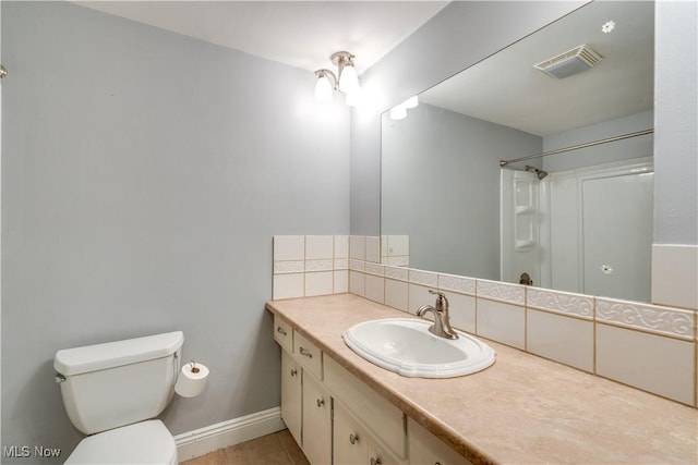 bathroom featuring toilet, tile patterned floors, vanity, and decorative backsplash