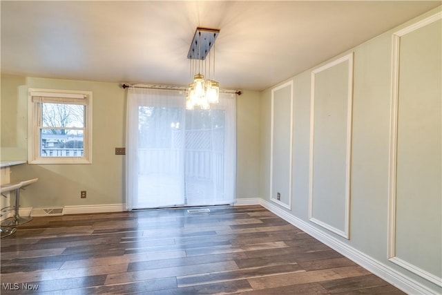 unfurnished dining area with a chandelier and dark hardwood / wood-style floors