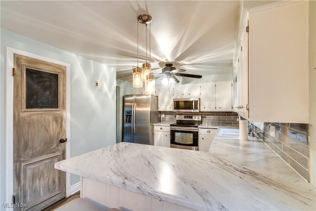 kitchen with stainless steel appliances, kitchen peninsula, pendant lighting, white cabinetry, and backsplash