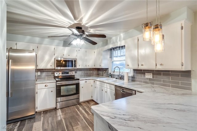 kitchen with stainless steel appliances, pendant lighting, decorative backsplash, sink, and white cabinetry