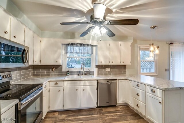 kitchen featuring kitchen peninsula, white cabinets, hanging light fixtures, and appliances with stainless steel finishes