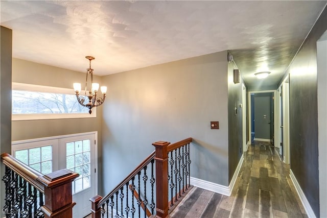 corridor featuring an inviting chandelier and dark wood-type flooring