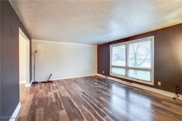 empty room with dark hardwood / wood-style flooring and wood walls