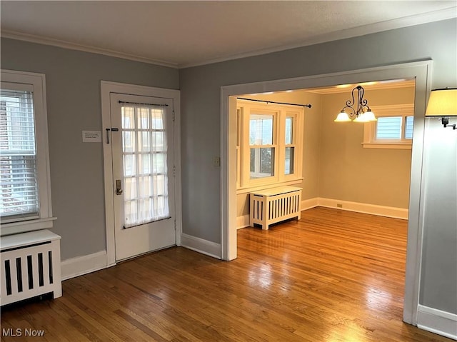 entryway featuring a chandelier, crown molding, a healthy amount of sunlight, and wood-type flooring