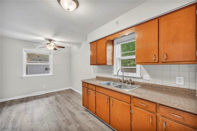 kitchen with tasteful backsplash, ceiling fan, sink, and light wood-type flooring