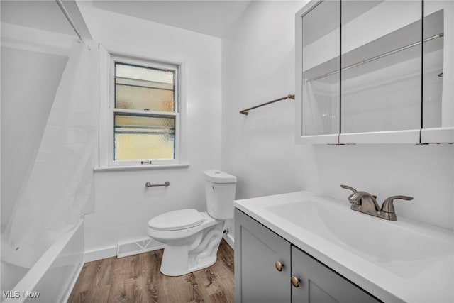 full bathroom featuring hardwood / wood-style flooring, shower / bath combination with curtain, toilet, and vanity