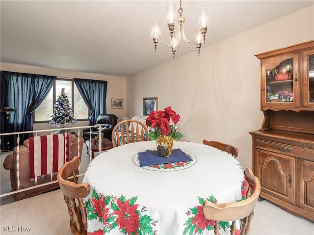 dining space featuring light carpet and an inviting chandelier