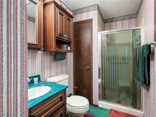 bathroom featuring vanity, toilet, and a shower with shower door