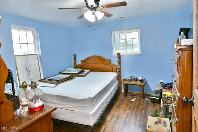 bedroom featuring ceiling fan, multiple windows, and dark hardwood / wood-style floors