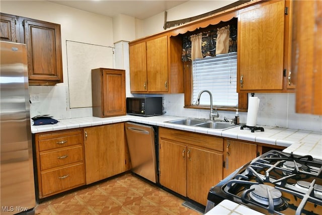 kitchen featuring decorative backsplash, appliances with stainless steel finishes, sink, and tile countertops