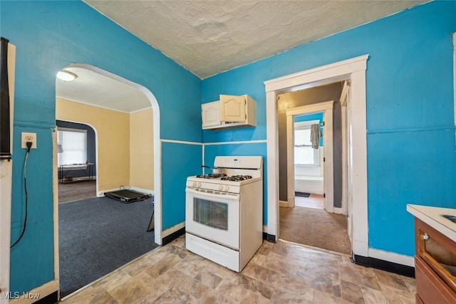 kitchen featuring light colored carpet, white gas range, and a textured ceiling