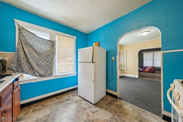 interior space with a textured ceiling, a healthy amount of sunlight, and light carpet