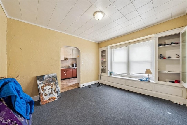 interior space with dark carpet and ornamental molding