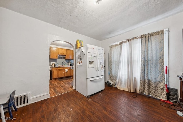 kitchen featuring dark hardwood / wood-style floors, white refrigerator with ice dispenser, and a textured ceiling