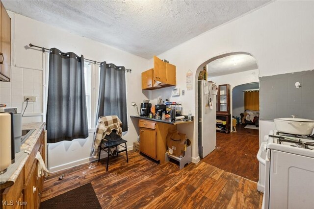 kitchen with dark hardwood / wood-style flooring, white appliances, and a textured ceiling