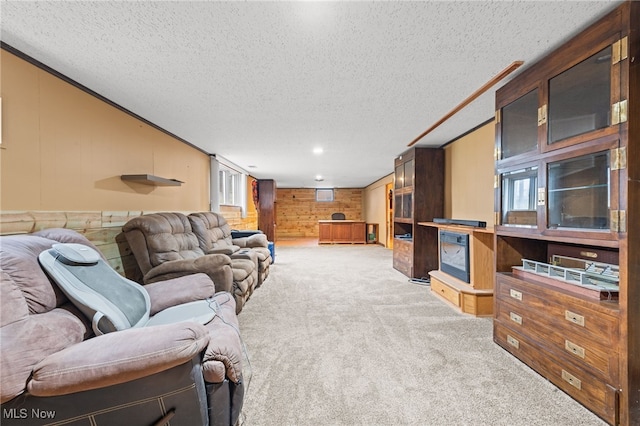 living room featuring light carpet, wooden walls, a textured ceiling, and ornamental molding