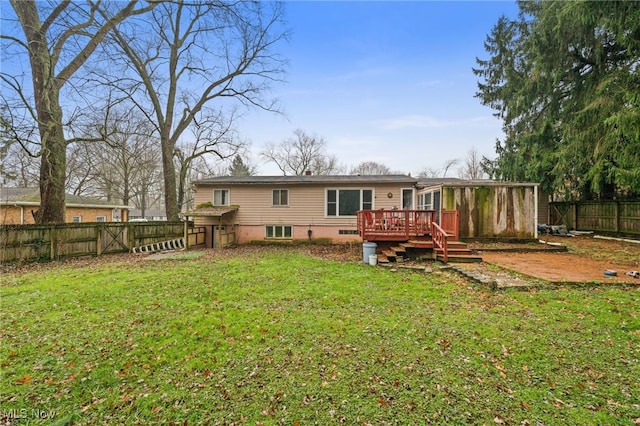 back of house featuring a lawn, a sunroom, and a wooden deck