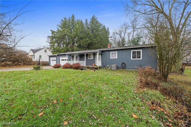 view of front facade with a garage, a porch, central AC, and a front lawn