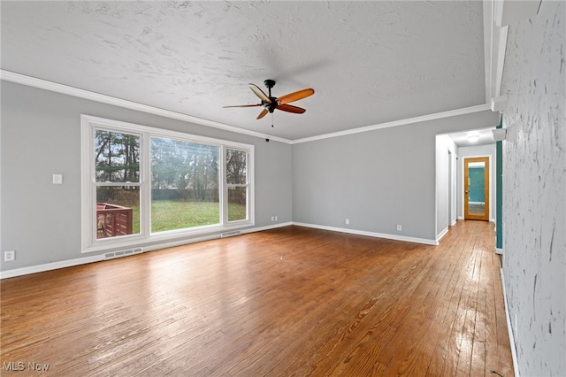 empty room featuring ceiling fan, crown molding, wood-type flooring, and a textured ceiling