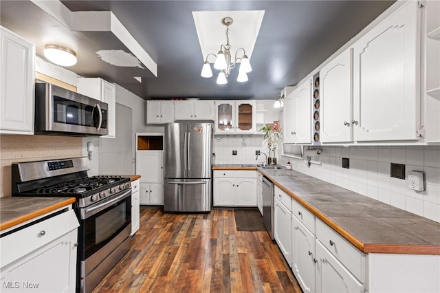 kitchen with tile countertops, stainless steel appliances, white cabinetry, and hanging light fixtures