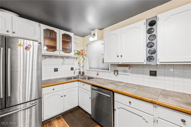 kitchen with stainless steel appliances, sink, tile countertops, dark hardwood / wood-style floors, and white cabinetry