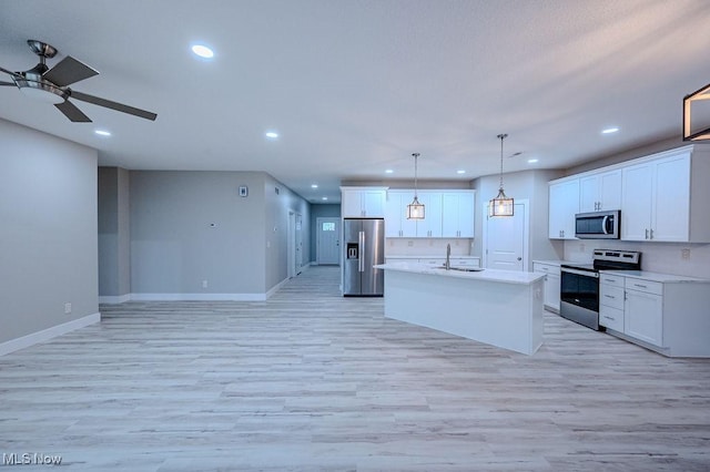 kitchen featuring white cabinets, appliances with stainless steel finishes, light hardwood / wood-style floors, and pendant lighting