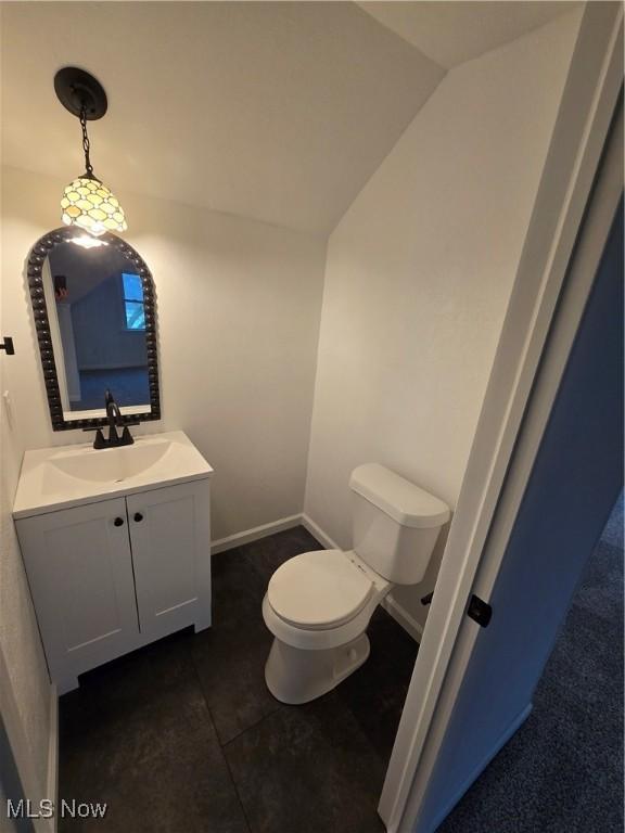 bathroom featuring tile patterned floors, vanity, lofted ceiling, and toilet