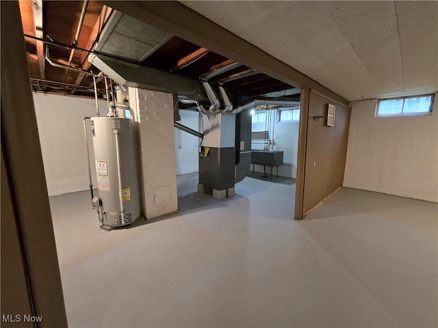 basement featuring heating unit, water heater, and sink