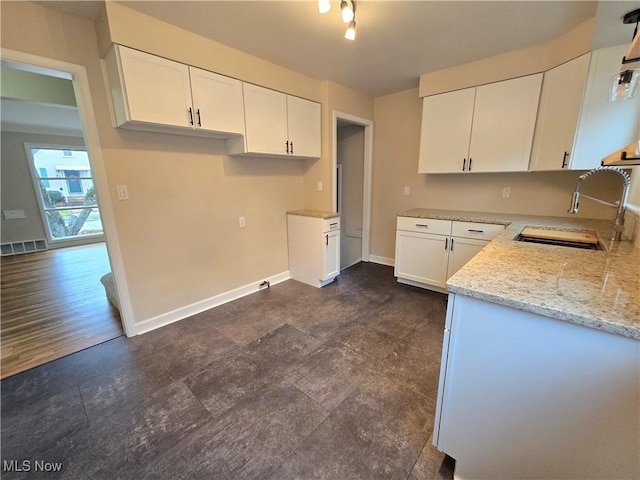 kitchen with white cabinets, light stone countertops, sink, and dark wood-type flooring