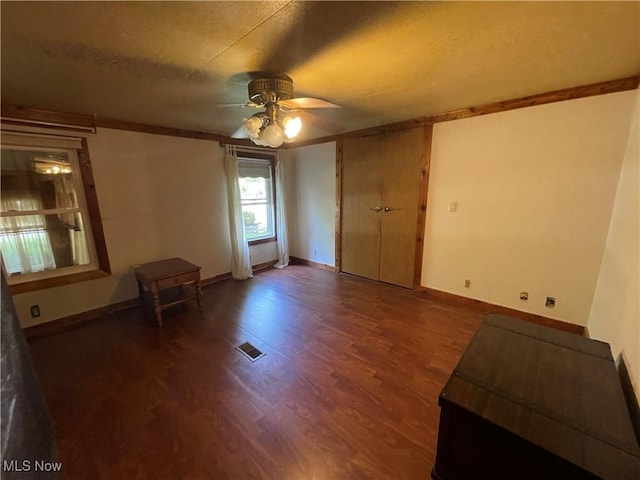 spare room with a textured ceiling, dark hardwood / wood-style flooring, ceiling fan, and crown molding