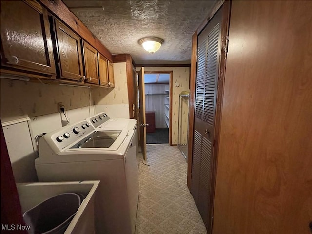 washroom with sink, cabinets, light colored carpet, a textured ceiling, and washer and clothes dryer