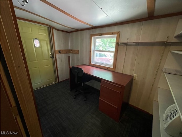 home office with wood walls and dark colored carpet