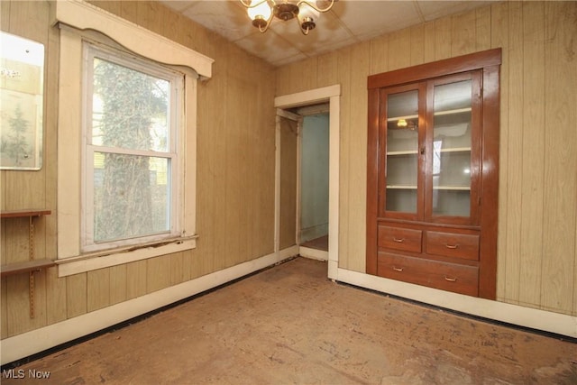 unfurnished room featuring a chandelier and wooden walls