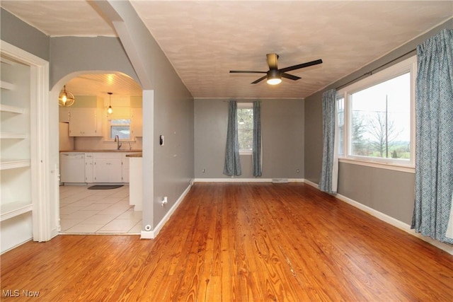 spare room featuring light wood-type flooring, ceiling fan, and a healthy amount of sunlight