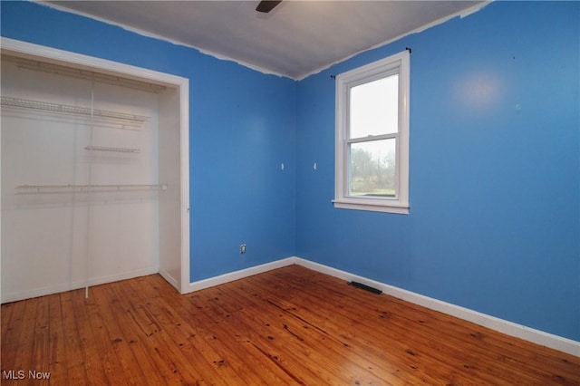 unfurnished bedroom with ceiling fan, a closet, and hardwood / wood-style flooring