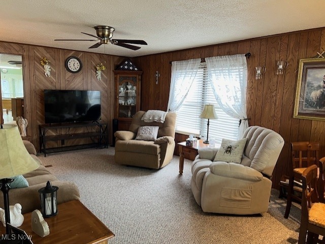 living room featuring a textured ceiling, light colored carpet, ceiling fan, and wooden walls