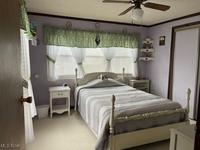 carpeted bedroom featuring ceiling fan, a textured ceiling, and ornamental molding