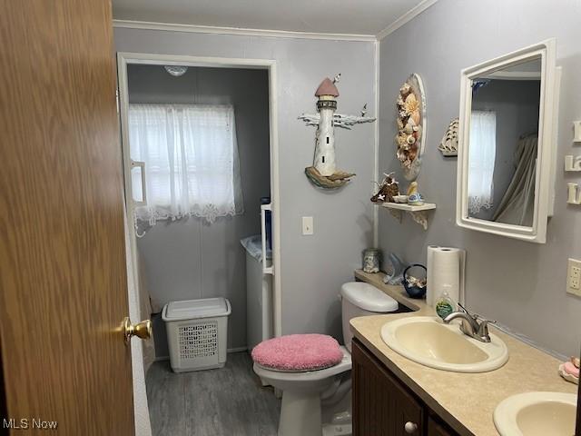 bathroom with toilet, hardwood / wood-style floors, vanity, and ornamental molding