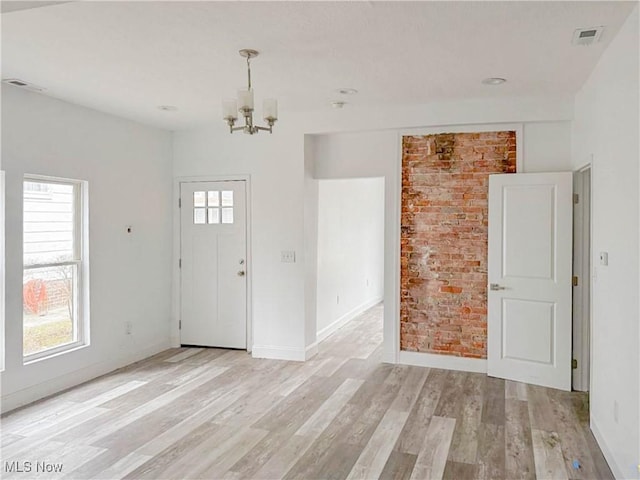 foyer with light wood-style floors, baseboards, visible vents, and a notable chandelier