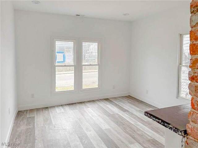 unfurnished room with baseboards, visible vents, and light wood finished floors