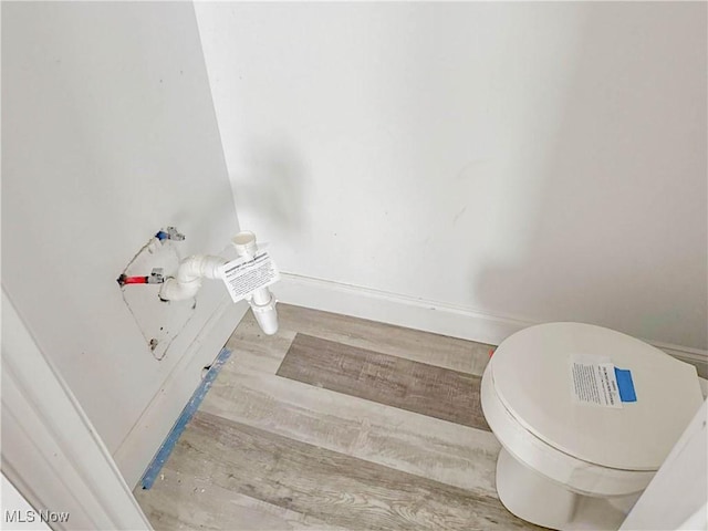 bathroom featuring wood finished floors, toilet, and baseboards