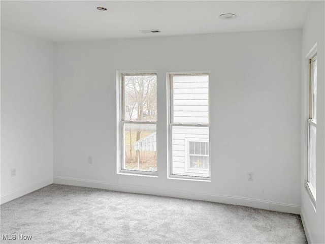 empty room with carpet flooring, visible vents, and baseboards